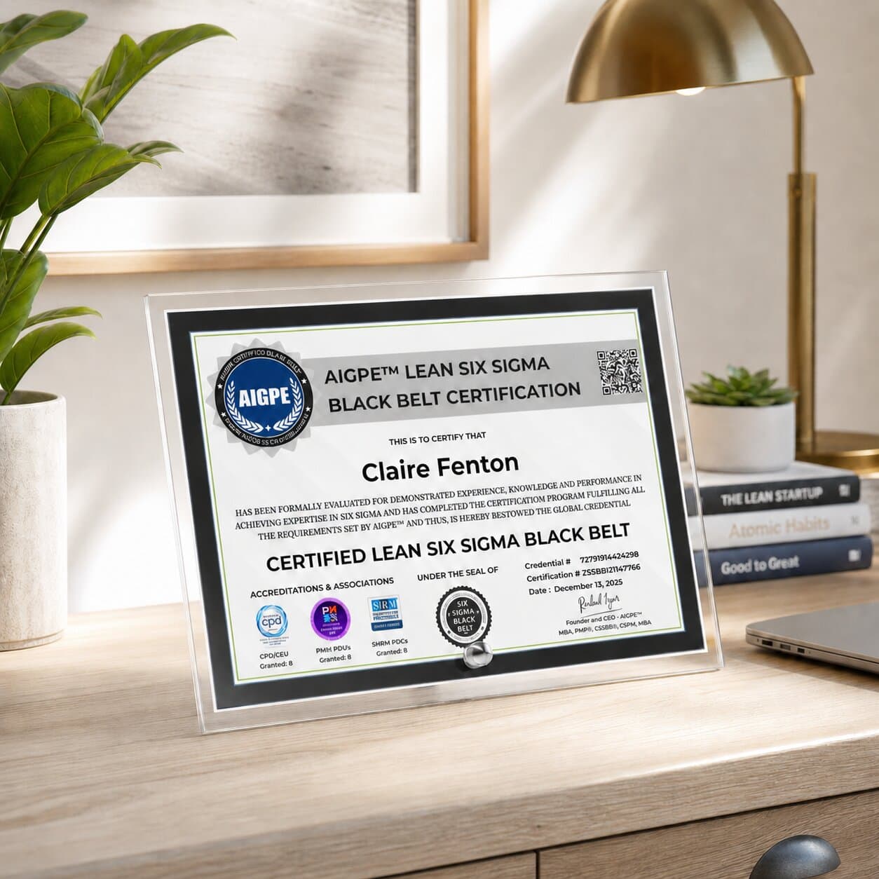Acrylic desktop display of an AIGPE Lean Six Sigma Black Belt certificate awarded to Claire Fenton, on a warm wood desk